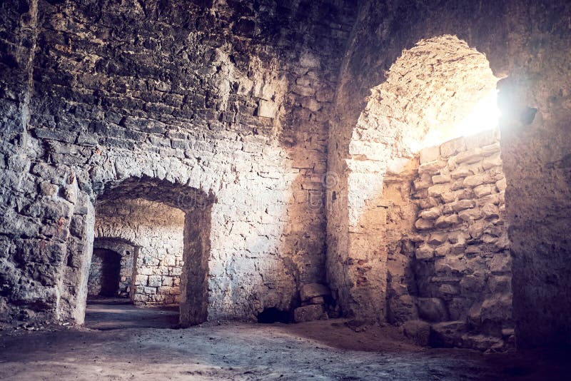 Ancient stone basement with arches. The sun breaks through window. Earthen floor stock photos
