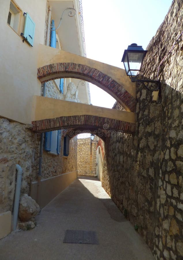 Arches connecting an old stone wall and a newer house over a narrow street on a hot summer day in Antibes royalty free stock photos