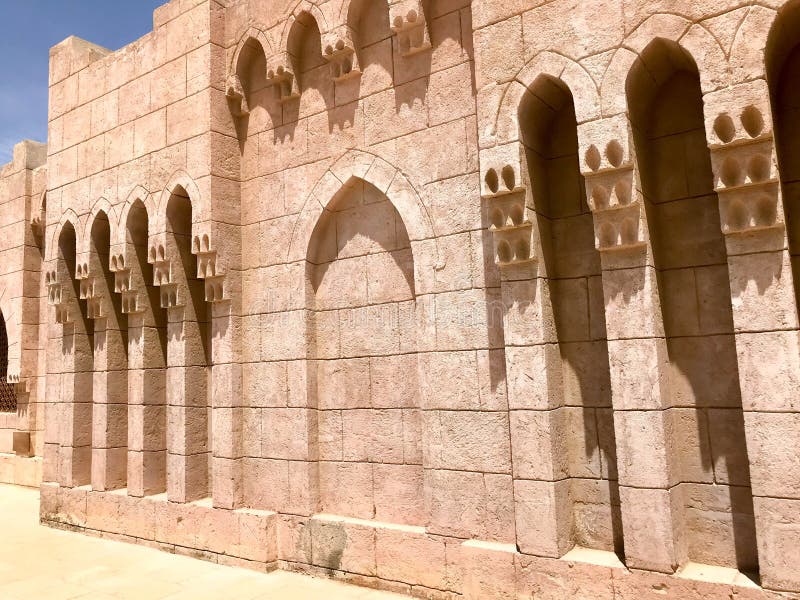 An old ancient yellow stone strong wall with arches in patterns and columns in an Arab Muslim Islamic warm tropical country in the royalty free stock photography