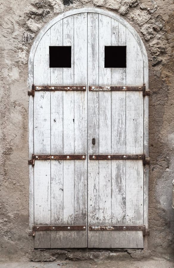 Old white wooden door with arch in stone wall royalty free stock image