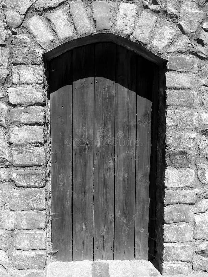 Old wooden door in a stone wall in black and white royalty free stock photo